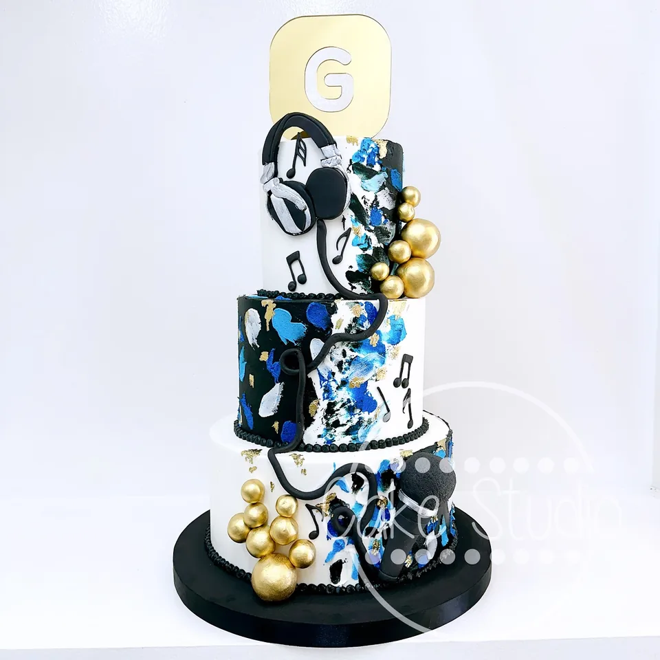 Pastel corporativo de tres niveles en azul, negro y blanco con audífonos, notas musicales y número 6, de Cake Studio